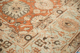 Low-pile corner of a vintage Tabriz rug with terracotta palmettes and a pale blue border.