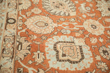 Close-up on the distressed Tabriz carpet's terracotta field with pale blue and ivory palmettes.