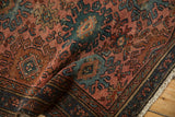 Folded vintage Persian Mehriban rug displaying dusty red field, blue vine border, fringe.