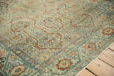 Detailed corner of a distressed Malayer rug with a Serbend vine border in dusty teal.