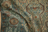 Time-softened texture of a distressed Malayer rug with geometric vines in dusty teal, sand, and copper.