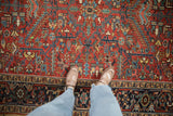Richly colored geometric motifs with serrated leaves on a cherry red vintage Heriz carpet.