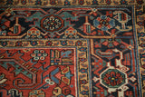 Geometric Turtle Samovar and vine motifs in the navy and sand borders of a hand-knotted Heriz rug.