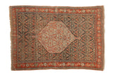 Antique Senneh rug with a hexagonal medallion, a dark Herati field, and a ruby red border.