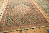 Full perspective of an antique Senneh rug highlighting its geometric medallion and allover Herati design.