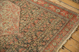 Antique Senneh rug corner showing ivory medallion, dark Herati field, and ruby red multi-band border.