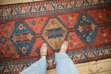 Serrated central medallions in brick red, navy blue, and camel on a vintage Kurdish rug.
