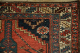 Corner detail of a vintage Kurdish rug's serrated leaf main border in red, teal, and sand.