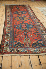 Angled view of a vintage Kurdish runner showing its serrated medallions and geometric border design.