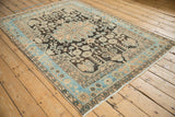 Angled view of a vintage Persian Hamadan rug showing its decorative sky blue border and distressed field.