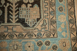 A geometric bird motif beside the sky blue and beige border of a distressed vintage Hamadan rug.