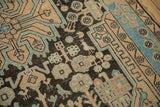 Worn texture and stylized bird motif in chocolate brown and sky blue on a Persian rug.