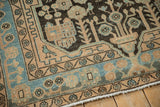 A sky-blue bird and geometric floral motifs on the border of a distressed Hamadan rug.