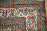 Corner detail of a fine antique Kerman rug with scrolled arabesques and intricate floral borders.
