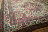 Detailed side view of an antique Kerman carpet's intricate floral borders and scrolled arabesque field.