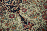 Close-up of the antique Kerman's fine pile, showing wear to the knot heads within the scrolled arabesques.