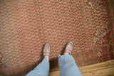 A perspective view of the distressed texture and staggered blossom design on a vintage Malayer rug.