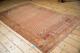 Distressed corner of a vintage Persian Malayer rug with tangerine orange pomegranate spandrels.