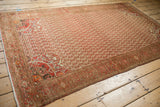 Angled view of the vintage Malayer rug showing its entire staggered blossom pattern and warm colors.
