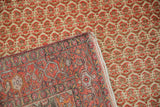 A corner of a vintage Malayer rug folded over to show its hand-knotted back and restored side selvage.