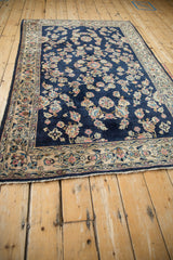 Angled perspective of a vintage Sarouk rug with floral sprays on a deep cobalt blue field.