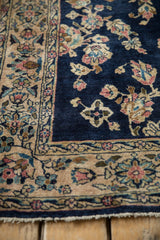 Corner view of a vintage Sarouk rug's platinum rose border and cobalt blue floral field.