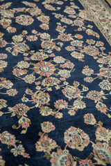 Angled view of the high-sheen wool pile and floral sprays on a vintage Sarouk rug.