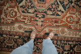 Antique Serapi carpet with brick red, navy, dusty blush, and emerald green floral arabesques.