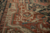 Detail of hand-knotted Antique Serapi carpet: brick red, navy, and blush floral vine motifs.