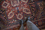 Vintage Heriz carpet showing deep cherry red field with navy blue geometric floral palmette designs.