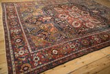 Vintage Heriz carpet corner detail, showing cherry red border, navy, gold, and blush Herati pattern.