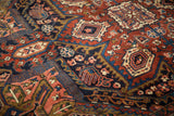 Vintage Heriz rug's cherry red and navy field featuring Herati and palmette motifs.