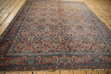 Vintage Tabriz rug corner showcasing brick red Herati border, navy, sky blue motifs, and short fringe.