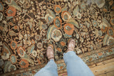 Close-up of distressed floral bouquets in orange and blue on a vintage Persian Malayer runner.