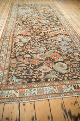 Angled perspective showing the full length and distressed floral design of a vintage Malayer runner.