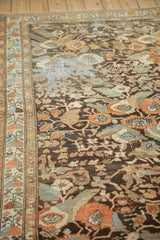 Angled view of a distressed Malayer runner showing foundation wear beside floral bouquets.