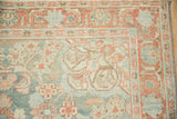 Corner view of a distressed Mahal rug showing the scrolled leaf border and time-softened pile.