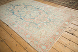 Angled view of a distressed Mahal rug's floral design and low-pile texture in soft blue and pink tones.