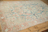 Angled view of a distressed Mahal rug showing the scrolled leaf border and soft, low-pile texture.