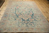 Low angle view across a distressed Persian Mahal rug, showing the soft patina on its floral design.