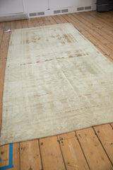 Angled view of a vintage Oushak runner, highlighting its distressed texture and muted floral design.