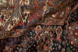 Detailed geometric patterns on vintage Heriz carpet in dusty burgundy, navy, and teal.