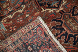 Vintage Heriz rug showing hand-knotted foundation, pile, white fringe, and geometric patterns.