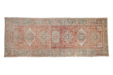 Distressed vintage Karaja runner with a column of geometric medallions in faded red and seafoam green.