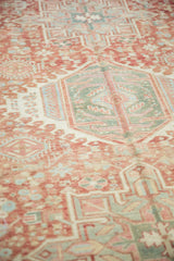 Low pile texture on a distressed Karaja rug's geometric medallion in soft brick red and seafoam green.