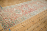 Angled view of a vintage Karaja runner showing its length, faded reds, and geometric medallions.