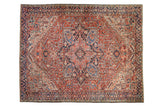 Vintage Persian Heriz carpet with a large geometric medallion in brick red, navy blue, and ivory.