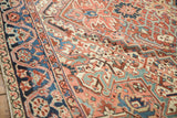 Intricate floral arabesques and palmettes in red and blue on a vintage Persian Heriz.