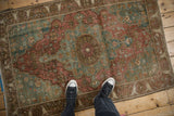 Distressed Farahan Sarouk rug corner, with faded raspberry, jade green, and arabesque floral border.