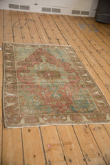 Antique Farahan Sarouk rug corner with distressed pile, bell-shaped arabesque border, faded red and green florals.